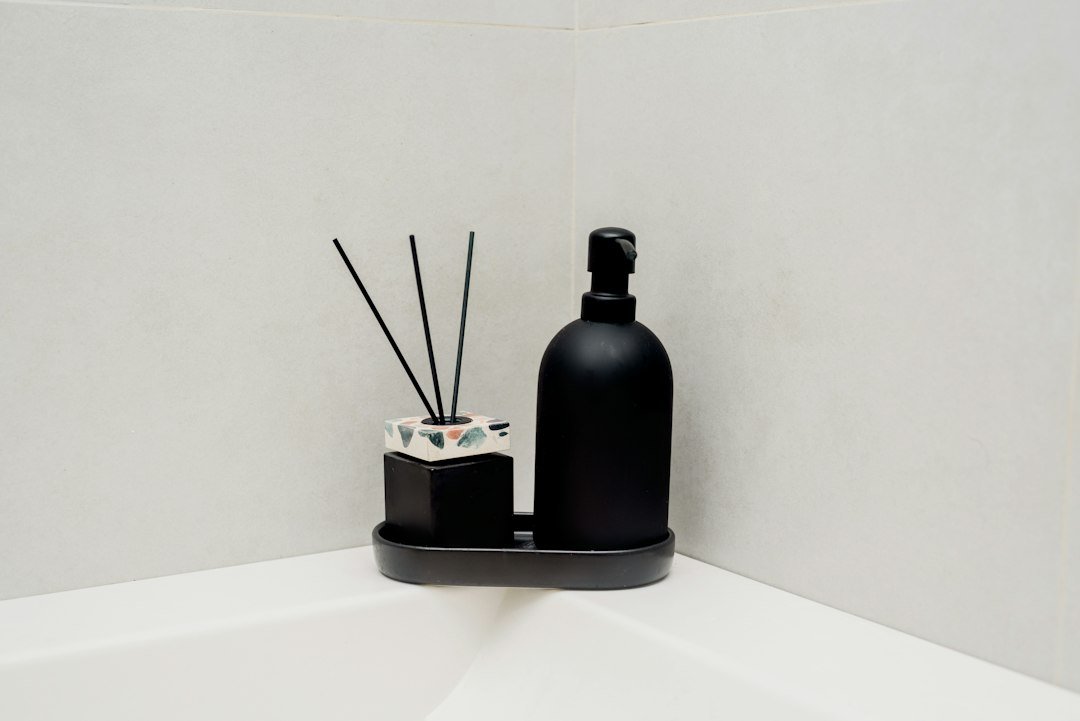 a black bottle and soap dispenser sitting on a shelf