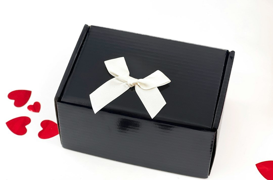 A black gift box with a white ribbon and hearts